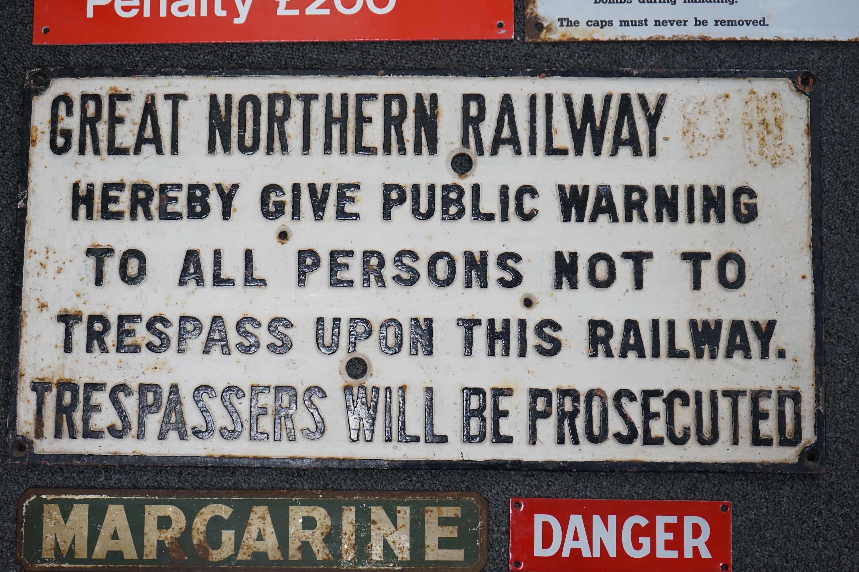 A Great Northern Railway cast iron sign; Trespassers Will Be Prosecuted, 28.5cm x 57cm, together with a WWII A W Bombs Precautions enamelled sign, a Margarine tin sign, a plastic BR Warning sign and a BR enamelled DANGER